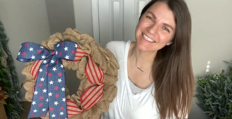 Woman holding rustic patriotic burlap wreath with striped ribbon and navy star bow