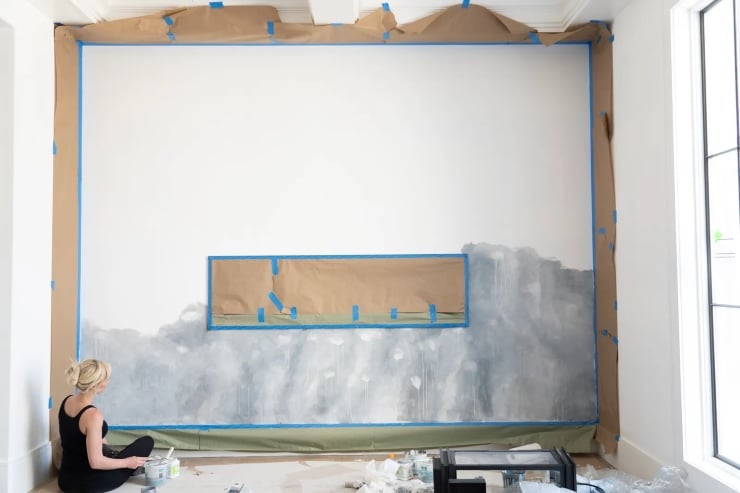 Woman painting large white living room wall