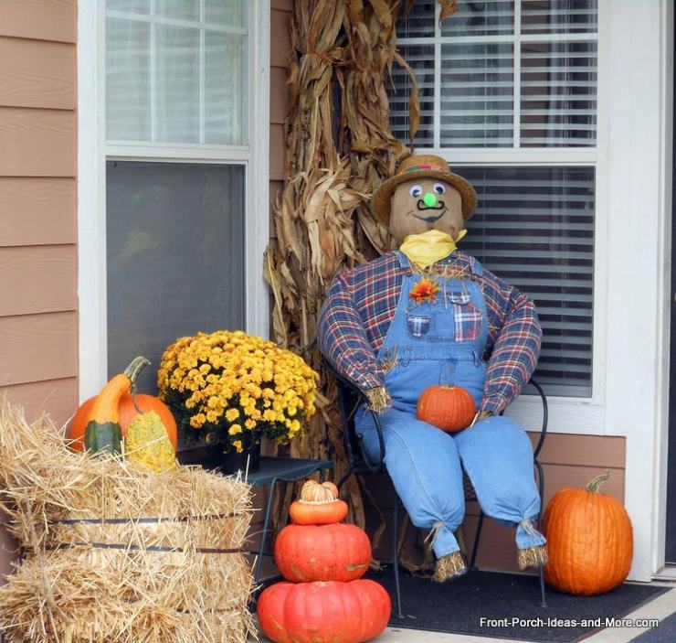 1. DIY burlap head scarecrow wearing a plaid shirt, straw hat, red bandana, and jeans beside a pumpkin.